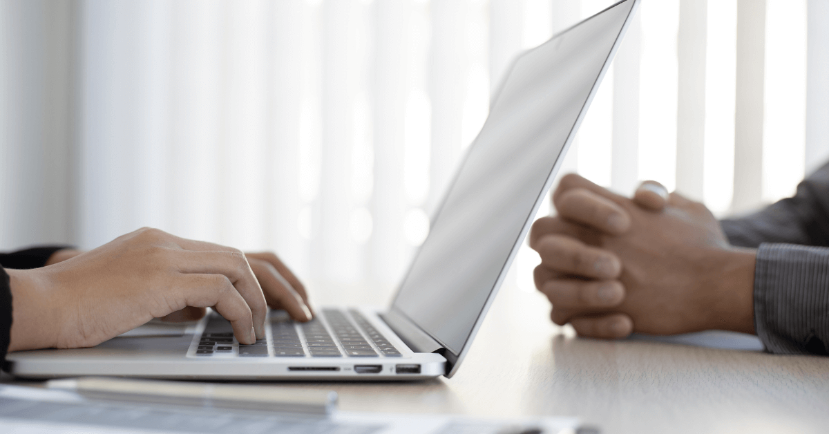 Photo of hands typing across from another set of hands on a desk