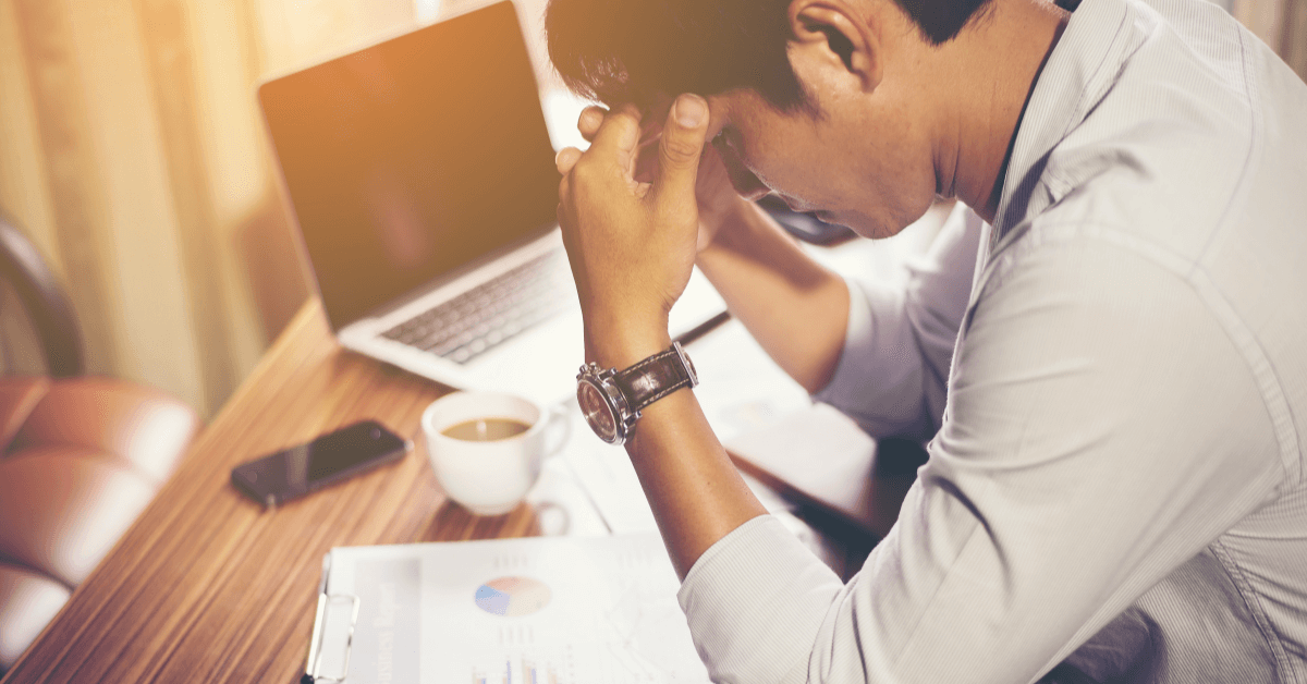 Image of a person at a desk with their head in their hands